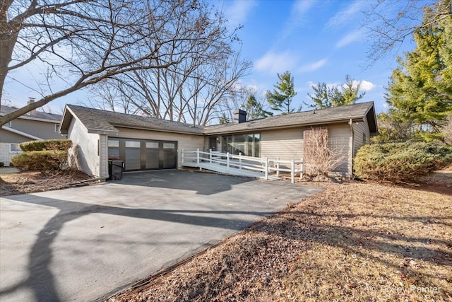 view of front of home with fence, a garage, driveway, and a chimney