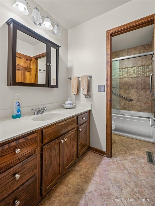 bathroom with vanity, baseboards, visible vents, toilet, and combined bath / shower with glass door