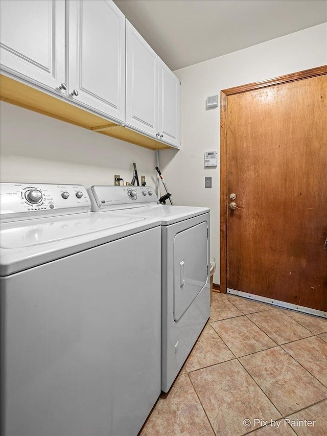 laundry area featuring washer and dryer, cabinet space, and light tile patterned flooring