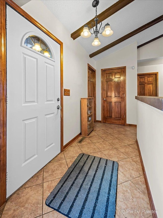 foyer entrance featuring light tile patterned floors, baseboards, an inviting chandelier, vaulted ceiling with beams, and a textured ceiling