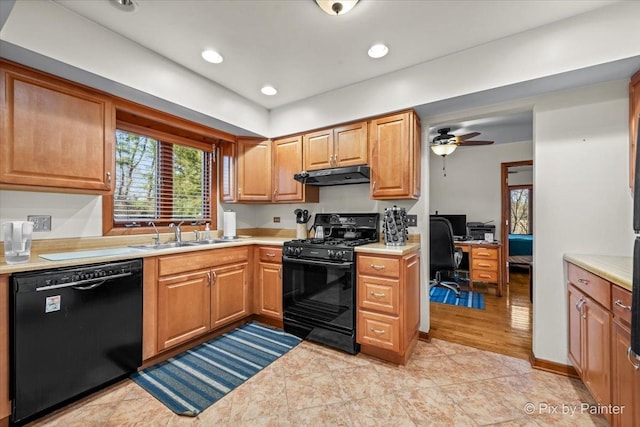 kitchen with a sink, black appliances, light countertops, and under cabinet range hood