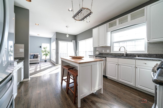 kitchen featuring dark wood-style floors, backsplash, appliances with stainless steel finishes, and a sink