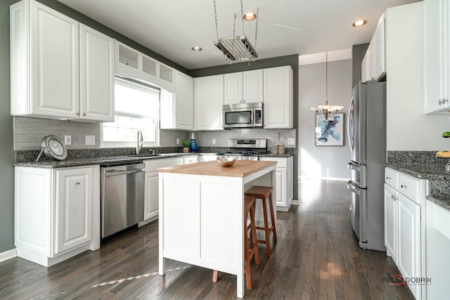 kitchen with backsplash, wooden counters, a center island, white cabinetry, and stainless steel appliances