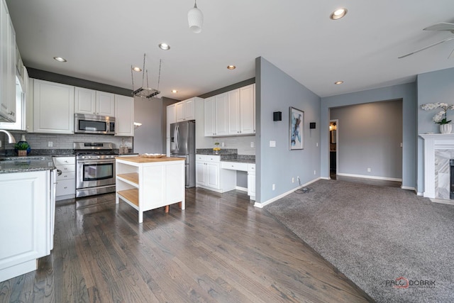 kitchen featuring tasteful backsplash, a premium fireplace, stainless steel appliances, white cabinetry, and open shelves