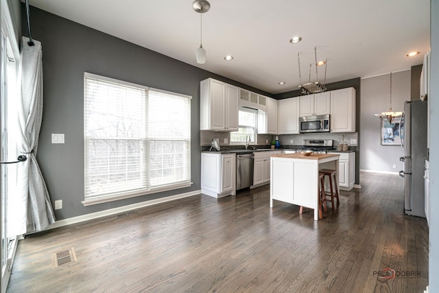 kitchen with visible vents, a sink, decorative backsplash, dark wood-type flooring, and stainless steel appliances