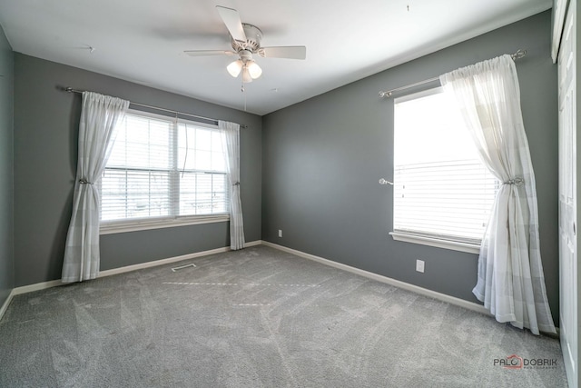 carpeted spare room featuring baseboards and ceiling fan