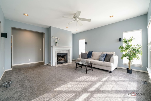 living area with a ceiling fan, baseboards, a high end fireplace, and carpet floors