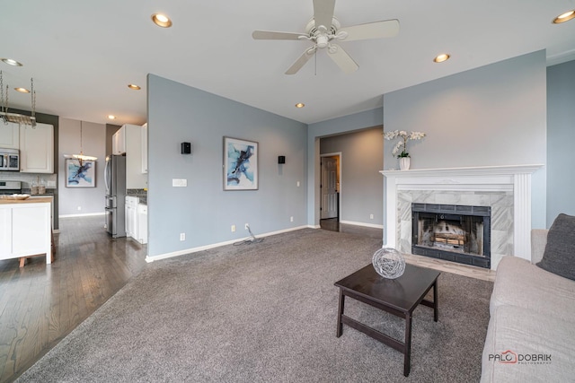 living room with baseboards, dark wood finished floors, recessed lighting, a fireplace, and ceiling fan