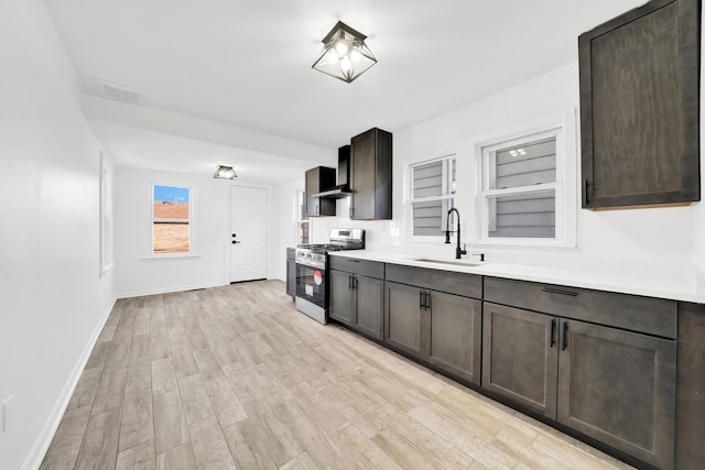 kitchen featuring gas range, light wood-style flooring, visible vents, and a sink