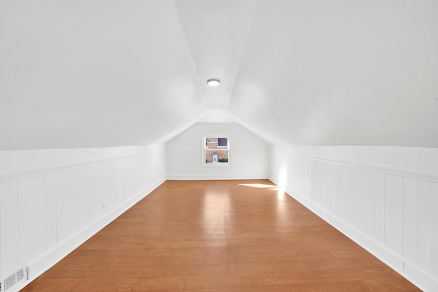 additional living space featuring visible vents, lofted ceiling, and wood finished floors