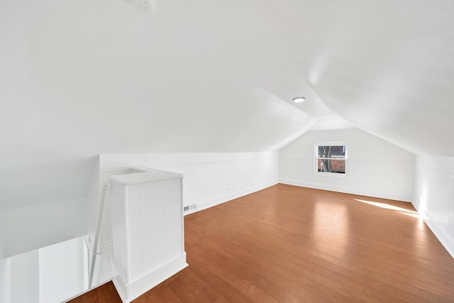 additional living space with hardwood / wood-style flooring and lofted ceiling