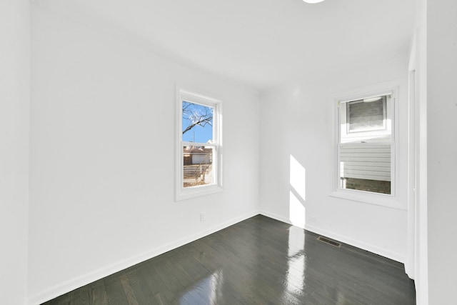 empty room featuring visible vents, baseboards, and dark wood-type flooring