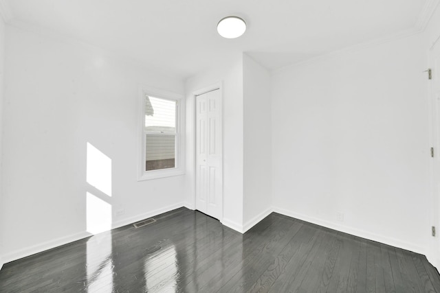 unfurnished room with dark wood-style floors, visible vents, and baseboards