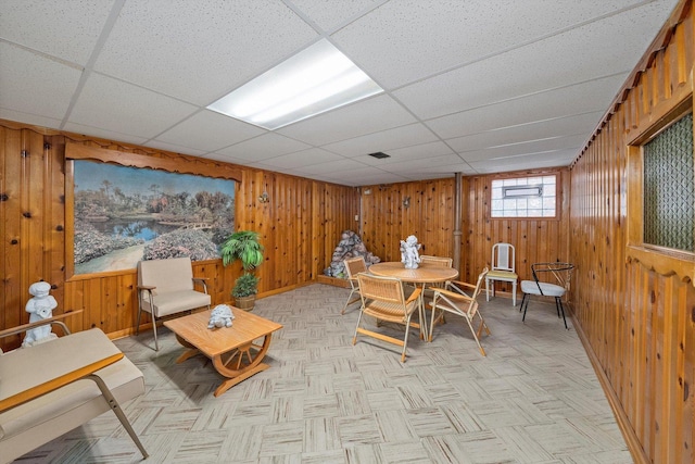 dining room with wooden walls, baseboards, and a drop ceiling