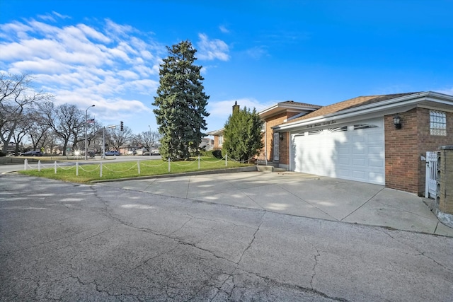 exterior space with brick siding, an attached garage, and driveway