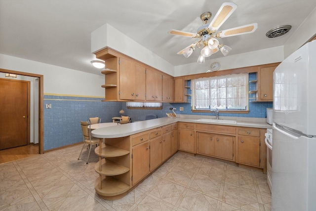 kitchen with visible vents, open shelves, freestanding refrigerator, a sink, and light countertops