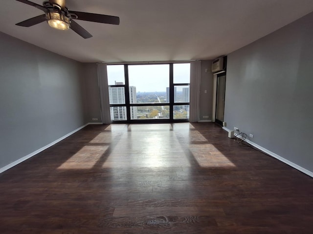 empty room with a wall mounted AC, expansive windows, dark wood finished floors, baseboards, and ceiling fan