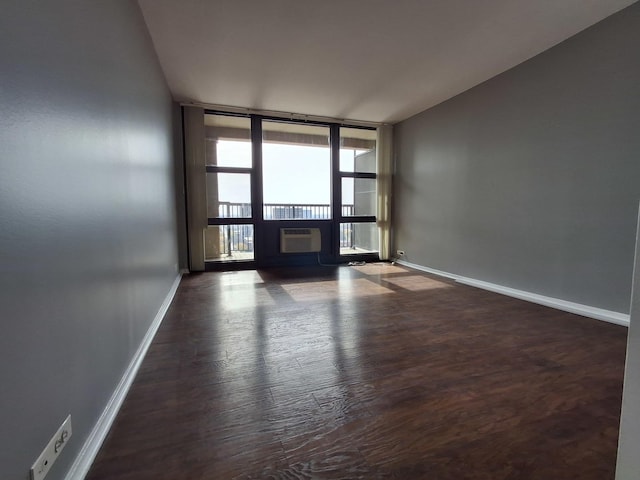 spare room with a wall mounted AC, wood finished floors, floor to ceiling windows, a fireplace, and baseboards