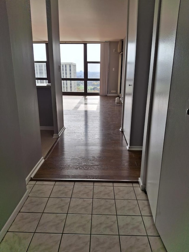 hallway with tile patterned floors, floor to ceiling windows, and baseboards