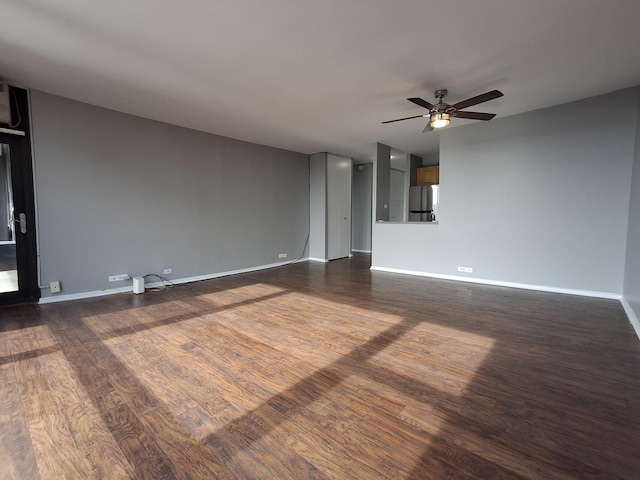 unfurnished room featuring baseboards, ceiling fan, and dark wood-style flooring