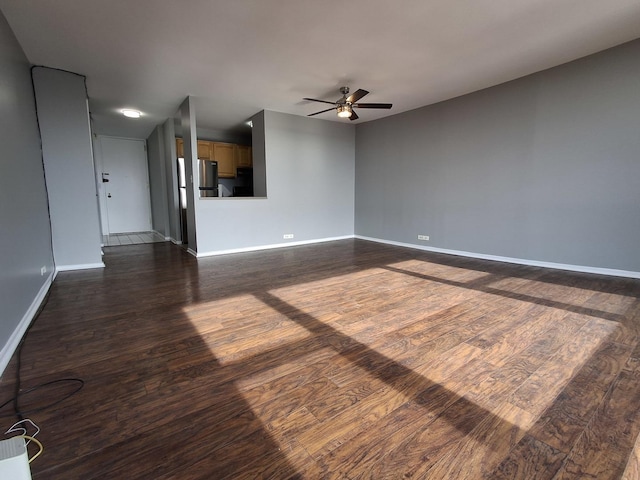 unfurnished living room featuring baseboards, ceiling fan, and dark wood-style flooring