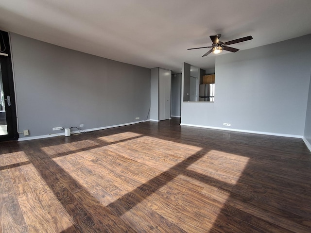 unfurnished room with dark wood-style floors, a ceiling fan, and baseboards