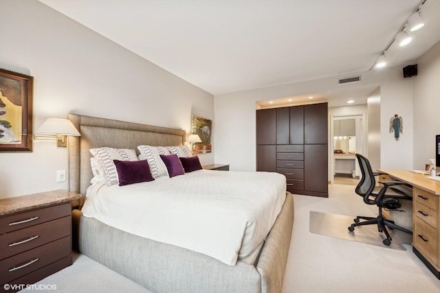 bedroom with visible vents, ensuite bathroom, light colored carpet, and track lighting