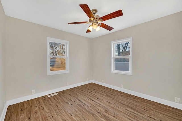 unfurnished room with visible vents, a ceiling fan, baseboards, and wood finished floors