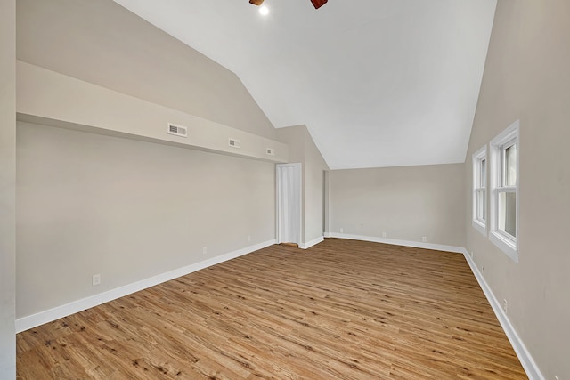 additional living space with visible vents, lofted ceiling, baseboards, and wood finished floors