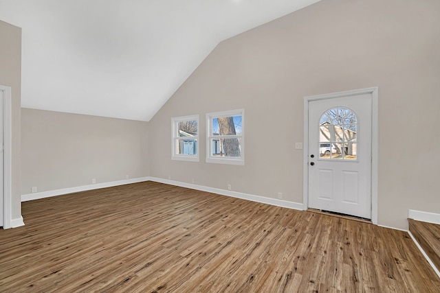 additional living space with baseboards, a healthy amount of sunlight, wood finished floors, and vaulted ceiling