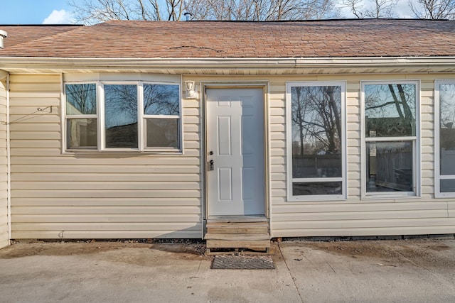 view of exterior entry with a shingled roof