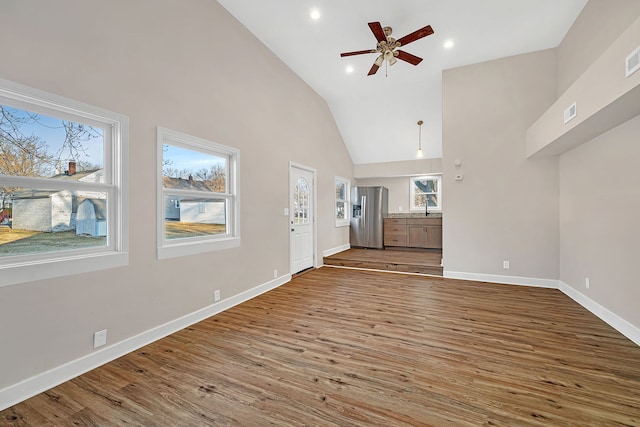 unfurnished living room with a wealth of natural light, baseboards, and wood finished floors