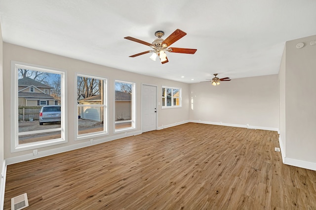 unfurnished living room with visible vents, a ceiling fan, baseboards, and wood finished floors