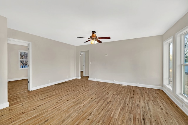 empty room featuring ceiling fan, baseboards, and light wood-style flooring