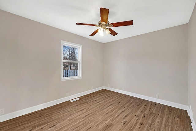 spare room featuring ceiling fan, visible vents, baseboards, and wood finished floors