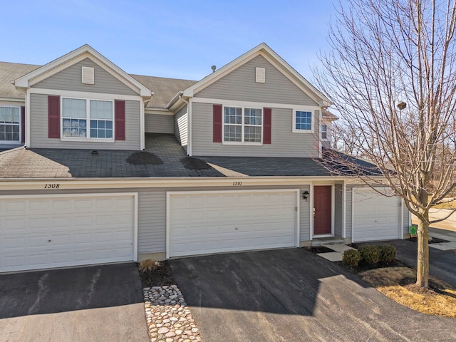 view of front facade with driveway, a shingled roof, and a garage