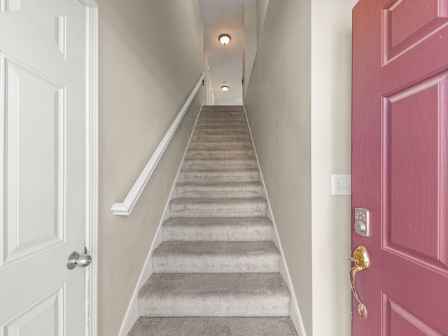 staircase featuring baseboards and carpet flooring