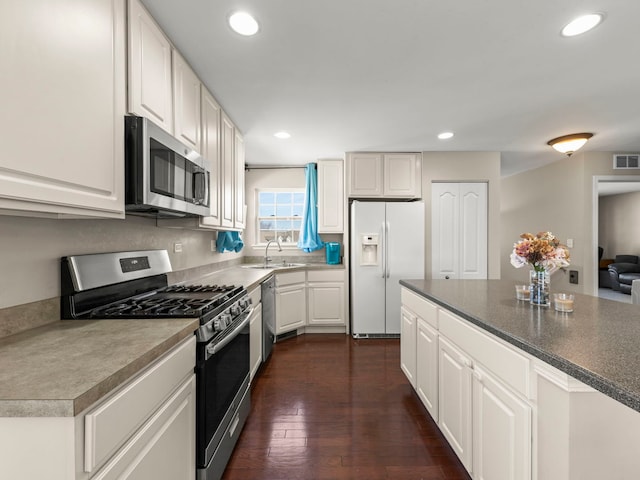 kitchen with a sink, white cabinetry, recessed lighting, stainless steel appliances, and dark wood-style flooring