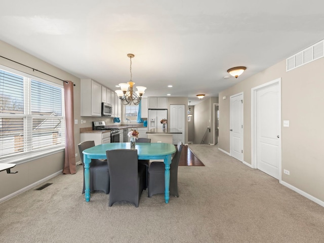 dining area featuring a notable chandelier, light colored carpet, visible vents, and a wealth of natural light