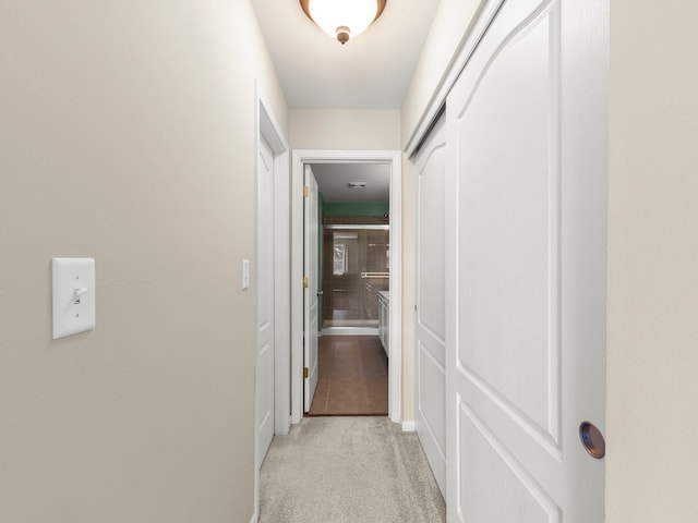 hallway featuring baseboards and light carpet