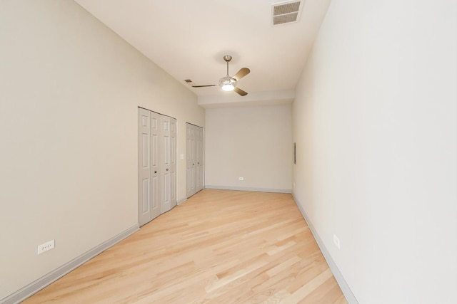 spare room featuring visible vents, baseboards, light wood-style flooring, and a ceiling fan