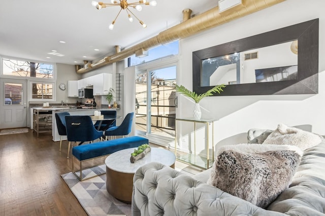 living area featuring visible vents, an inviting chandelier, and dark wood-style flooring