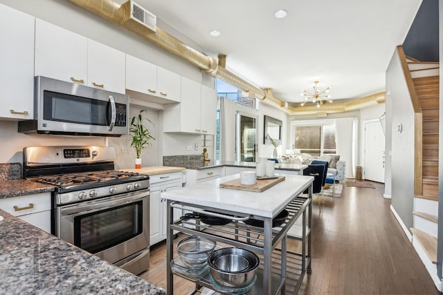 kitchen featuring visible vents, an inviting chandelier, appliances with stainless steel finishes, white cabinetry, and open floor plan