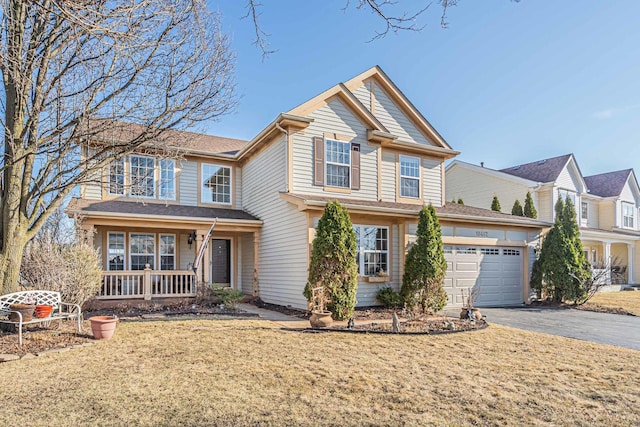 view of front of house with a porch, a garage, driveway, and a front lawn