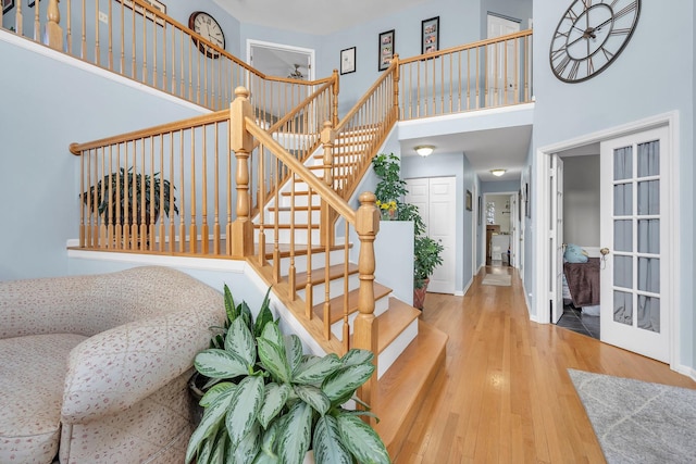 stairway with a high ceiling, wood finished floors, and baseboards