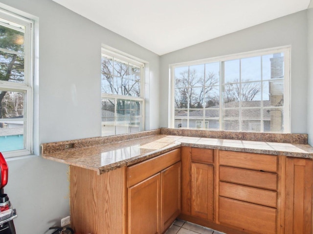 kitchen featuring tile countertops, light tile patterned flooring, and brown cabinetry