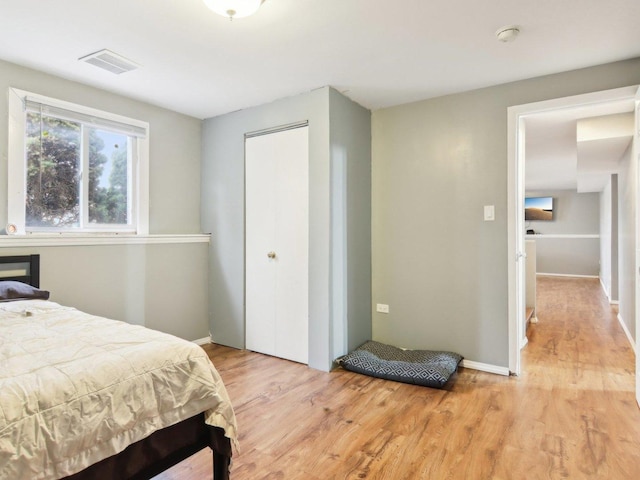 bedroom with light wood-style floors, visible vents, and baseboards