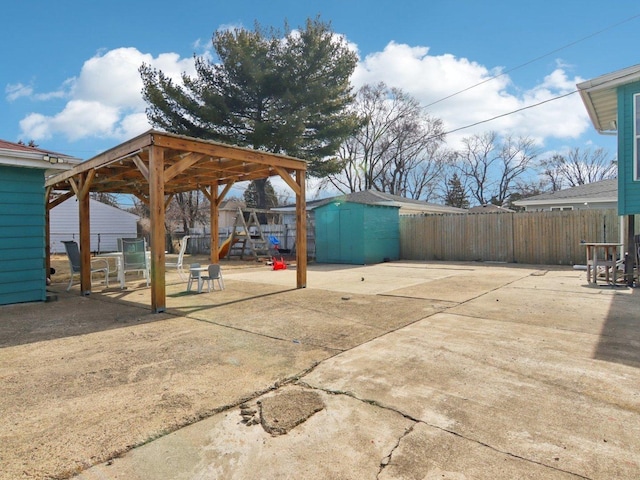 view of patio / terrace featuring an outdoor structure, fence, and a shed