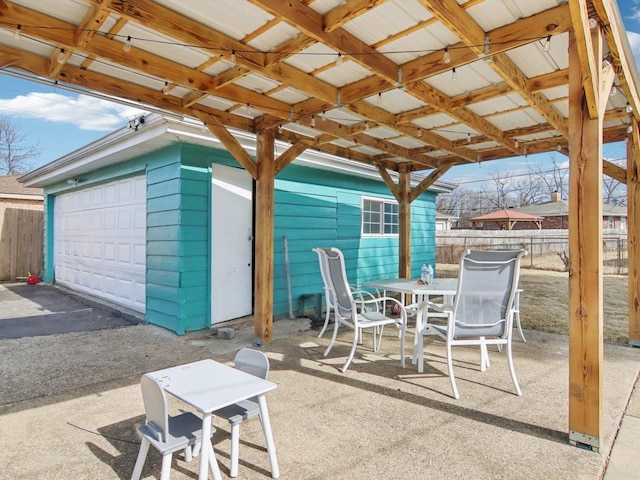 view of patio / terrace with outdoor dining area, a garage, and fence