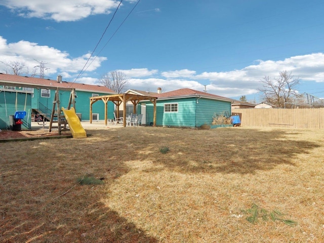 rear view of property with a gazebo, a playground, a yard, and fence